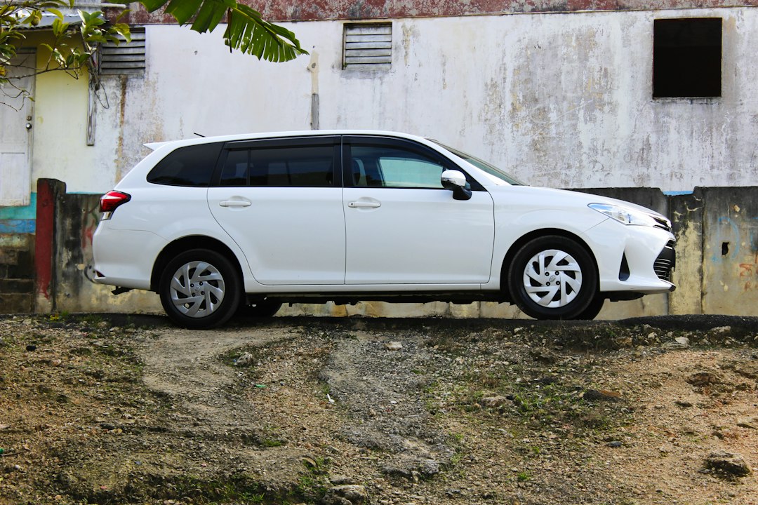White station wagon viewed from the side on a gravel lot