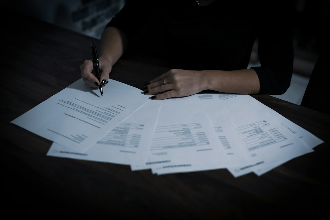 Hands writing on a document spread across a desk