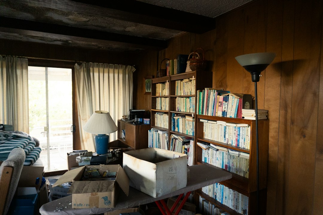A living room with bookshelves, curtains, and open boxes.