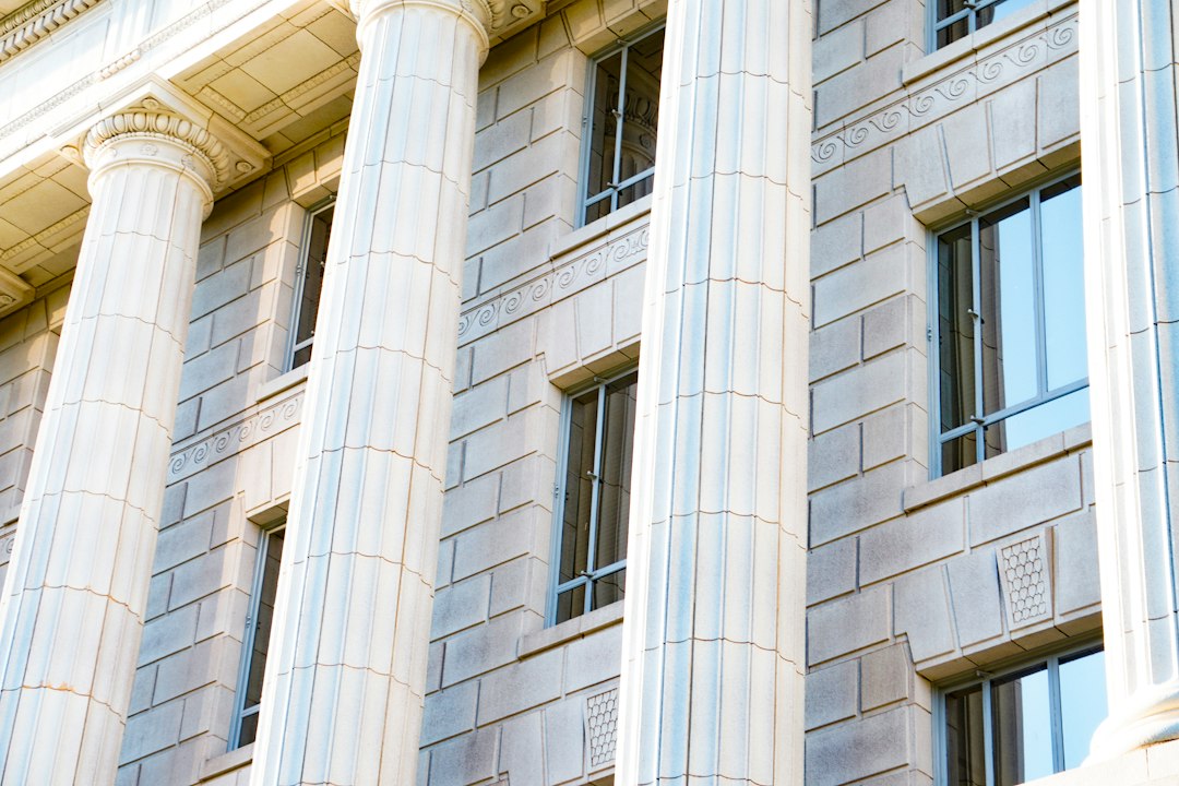 Tall white columns and windows on a stone building facade.