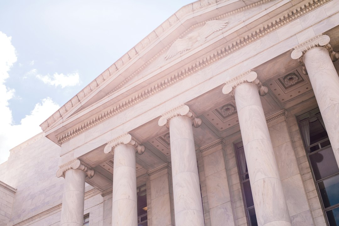 Sunlight falling across the columns of a white classical building.