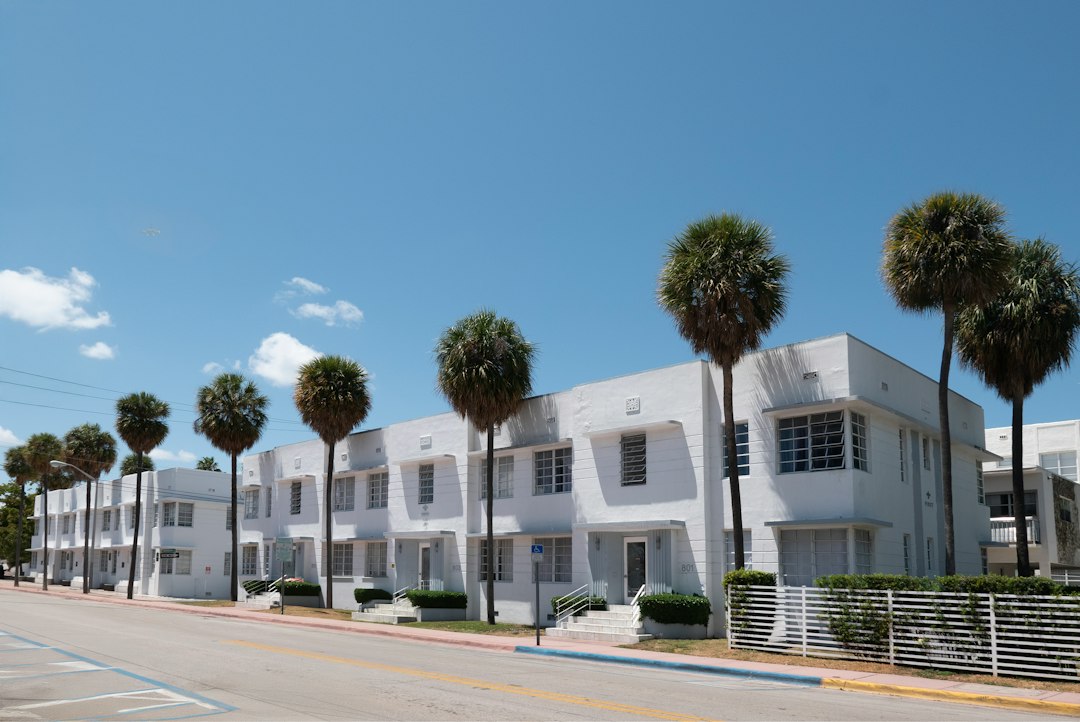 White low-rise residential buildings along a palm-lined street.