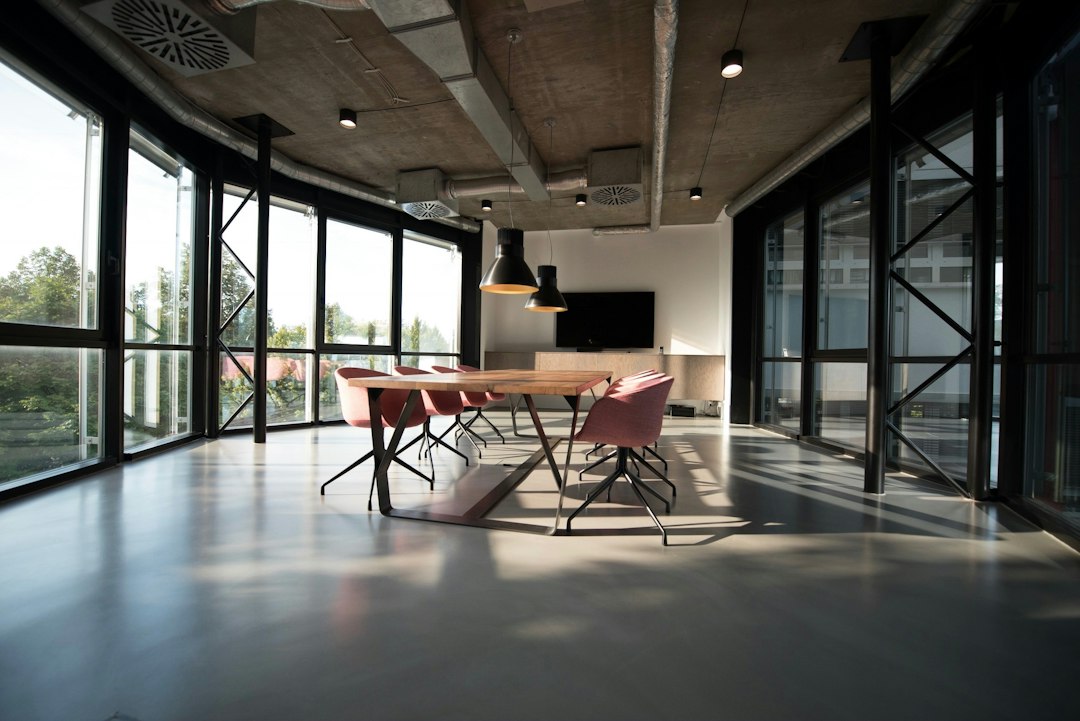 An empty modern meeting room with a long table and large windows.