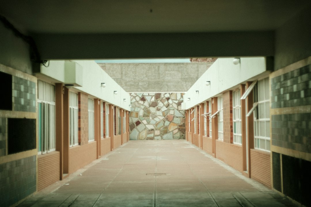 An empty covered corridor with classroom doors along both sides.
