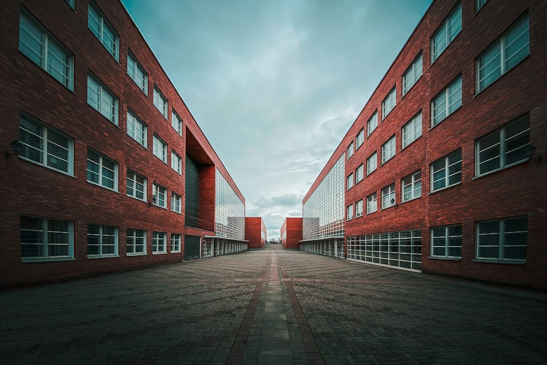 A paved courtyard between two red brick school buildings.