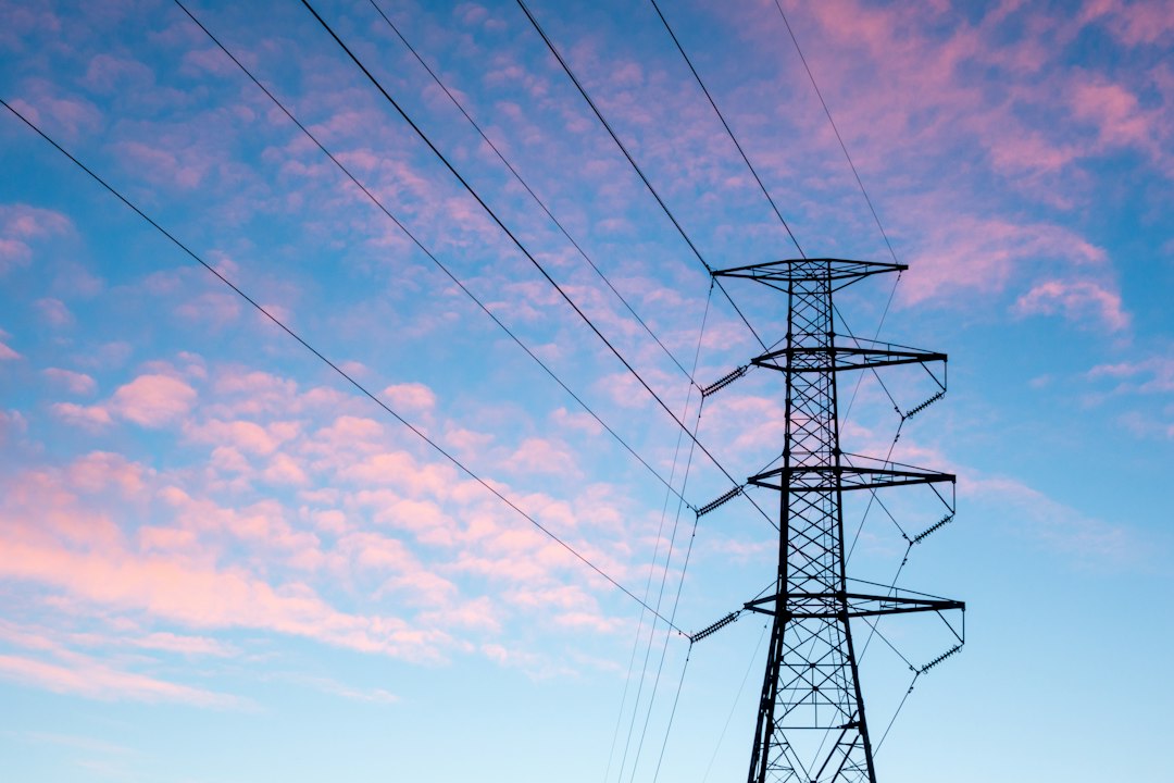 An electricity pylon beneath pink clouds and a blue evening sky.