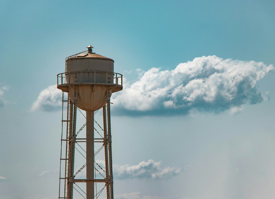 An elevated metal water tank against blue sky and clouds.