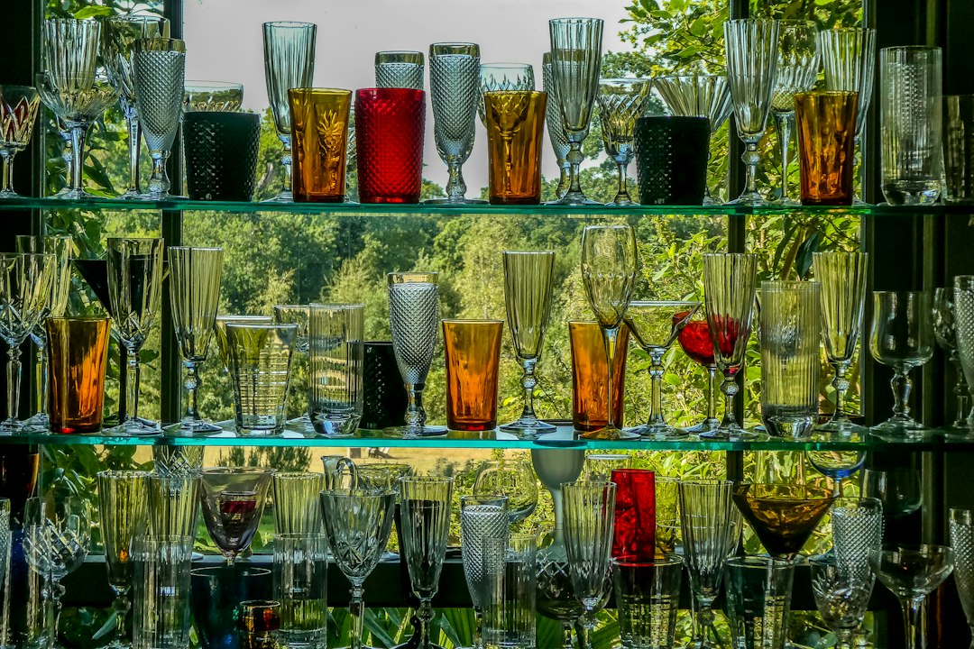 Colorful drinking glasses arranged across glass shelves.