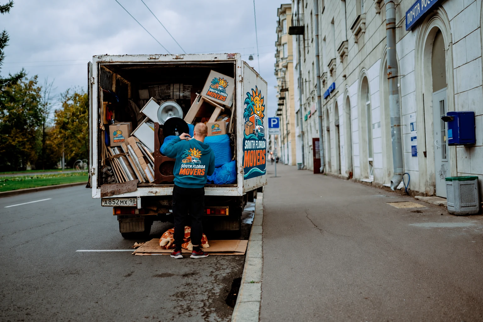 A worker wearing a South Florida Movers branded top loads furniture into a truck with matching branding.