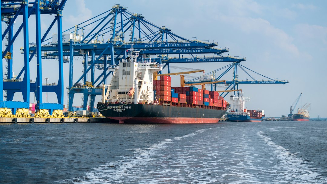 A cargo ship carrying containers beside port cranes.