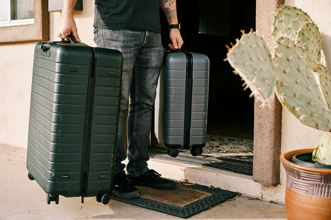 Two hard-shell suitcases being carried across a doorway