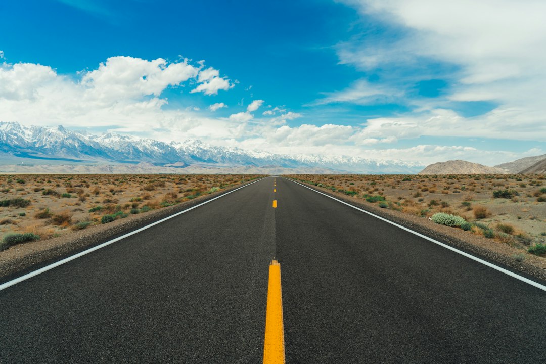Straight paved road crossing an open landscape toward mountains