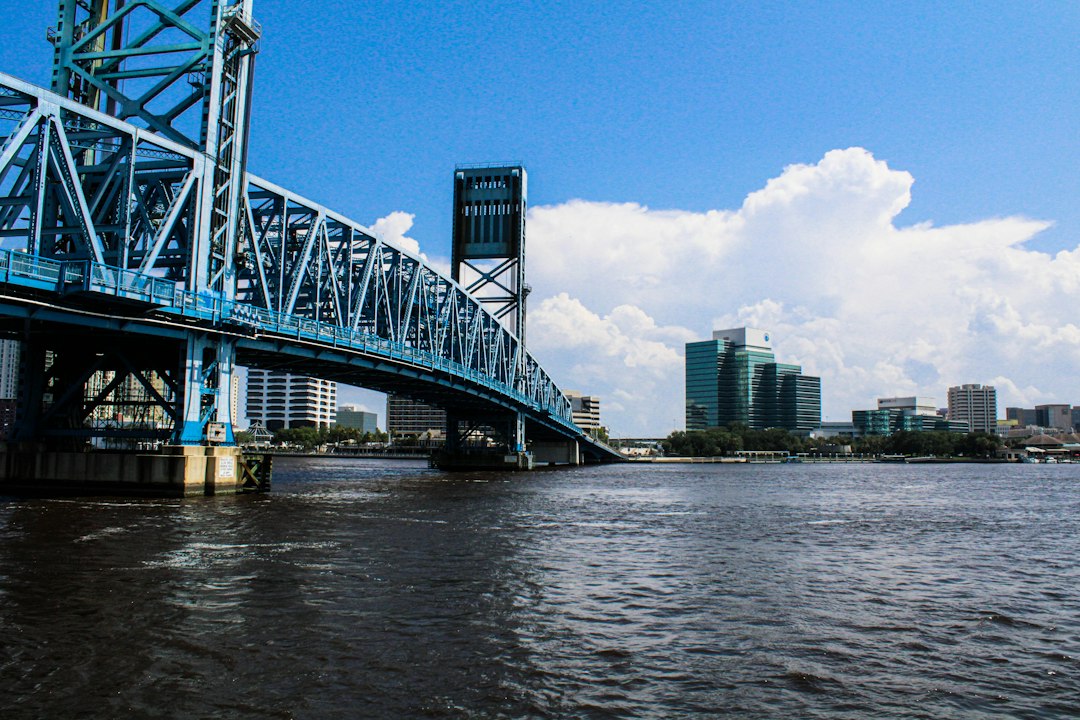 Blue steel Main Street Bridge spanning the St. Johns River in Jacksonville, with downtown buildings in the distance