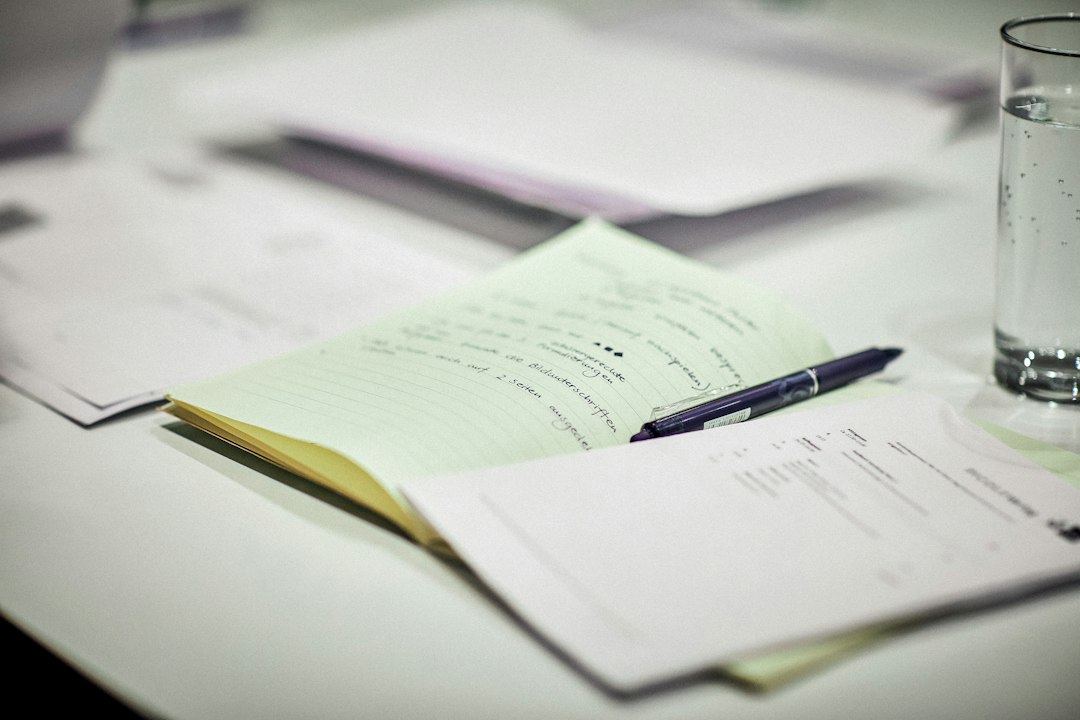 Open notebook with handwritten notes and a pen beside loose papers.