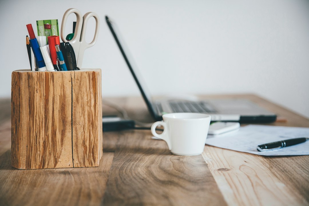 Desk with a wooden stationery holder, white mug, and a computer.