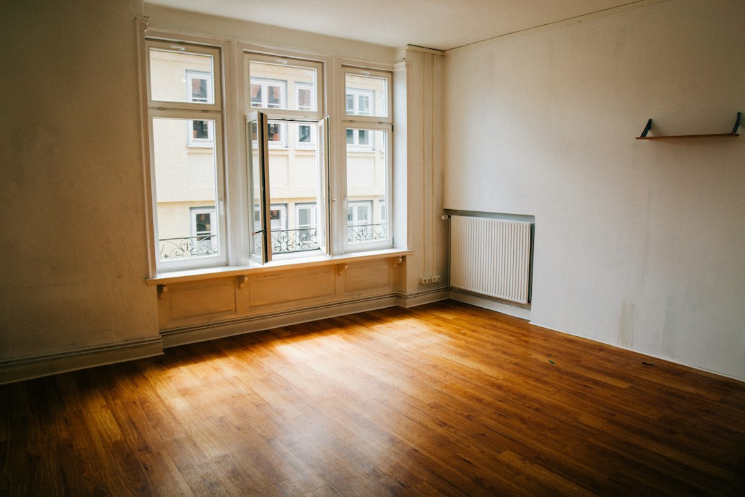 Sunlit empty room with wood flooring and a radiator