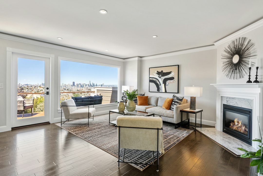 Apartment living room with a gray sofa, fireplace, and large windows overlooking the city