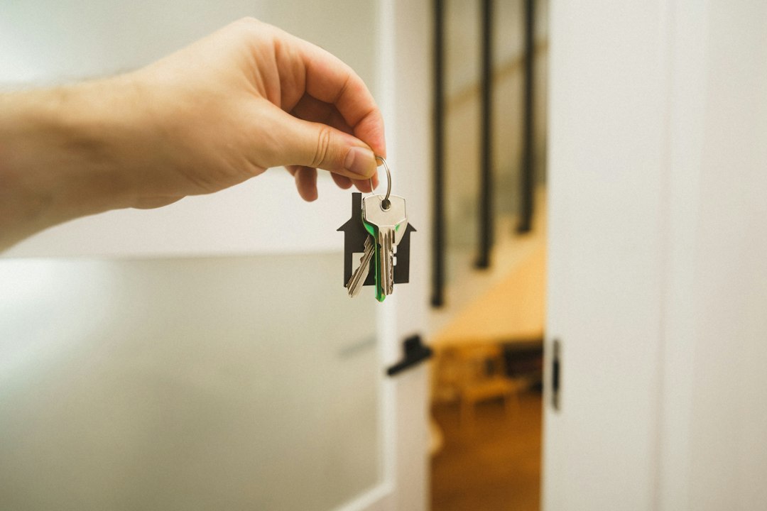 Hand holding keys with a house-shaped keychain