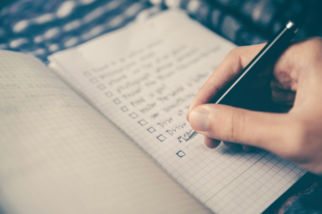Hand marking a handwritten checklist in a notebook