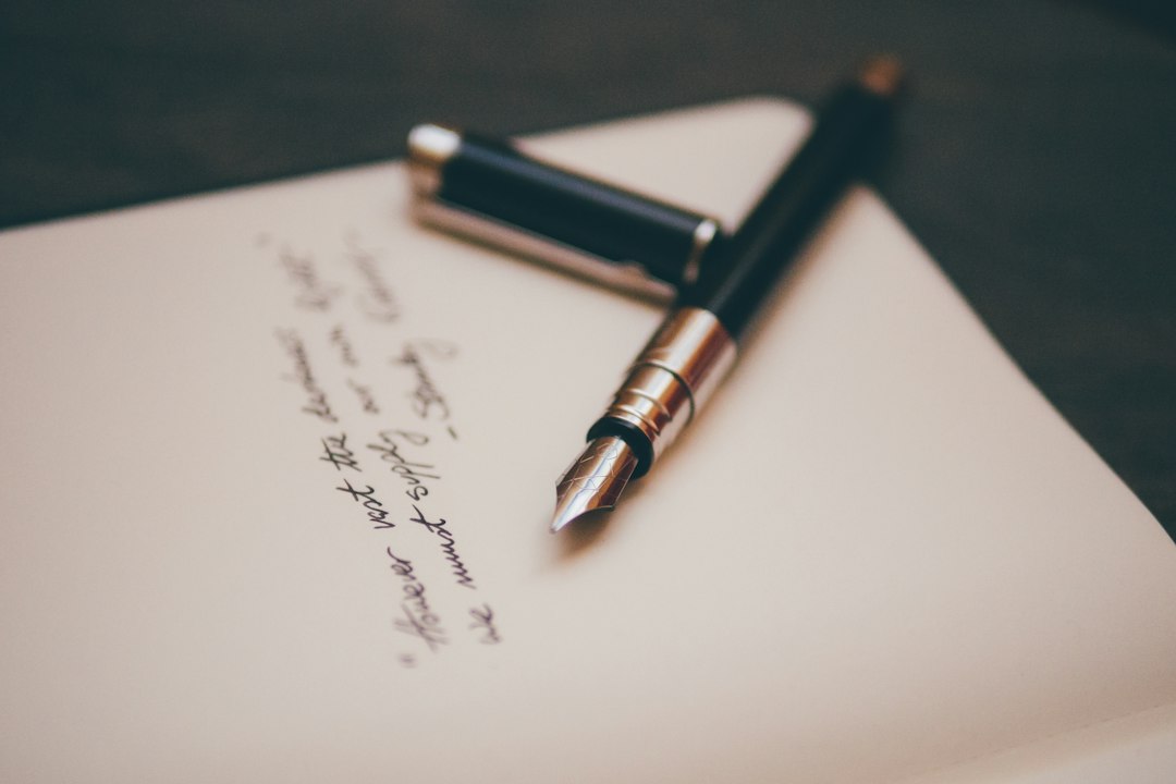Fountain pen beside handwriting on an open notebook
