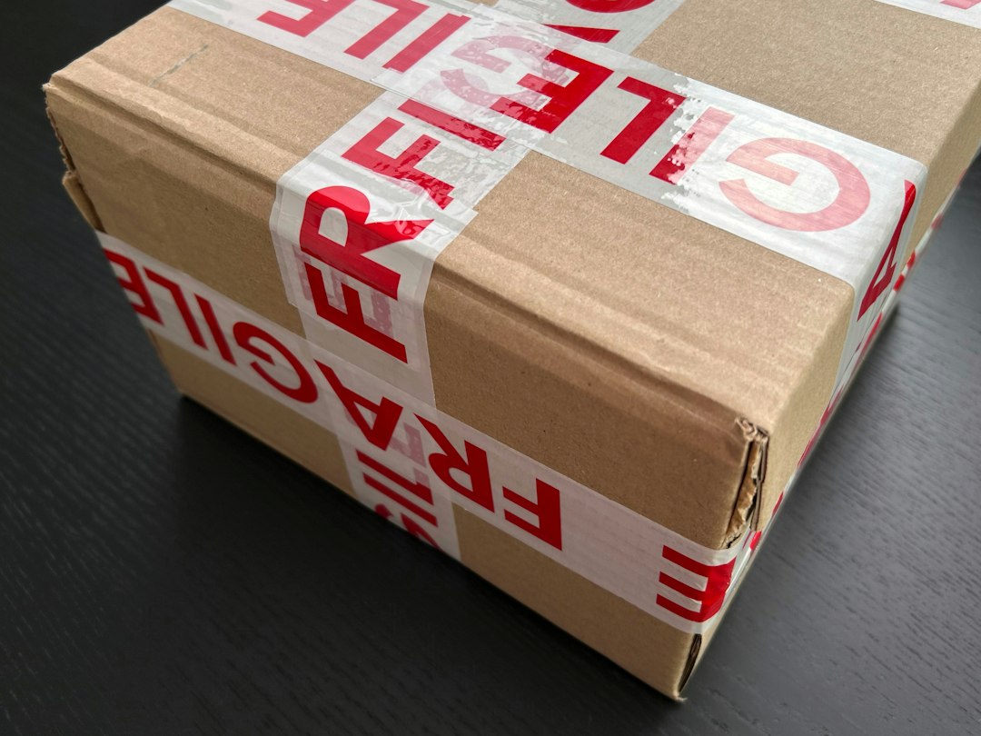 Close-up of a cardboard box sealed with red and white fragile tape.