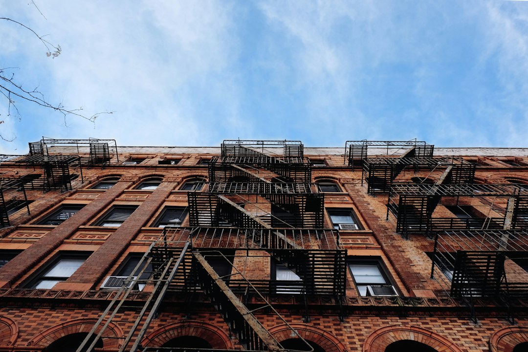 Looking up at a brick apartment building with metal fire escapes.