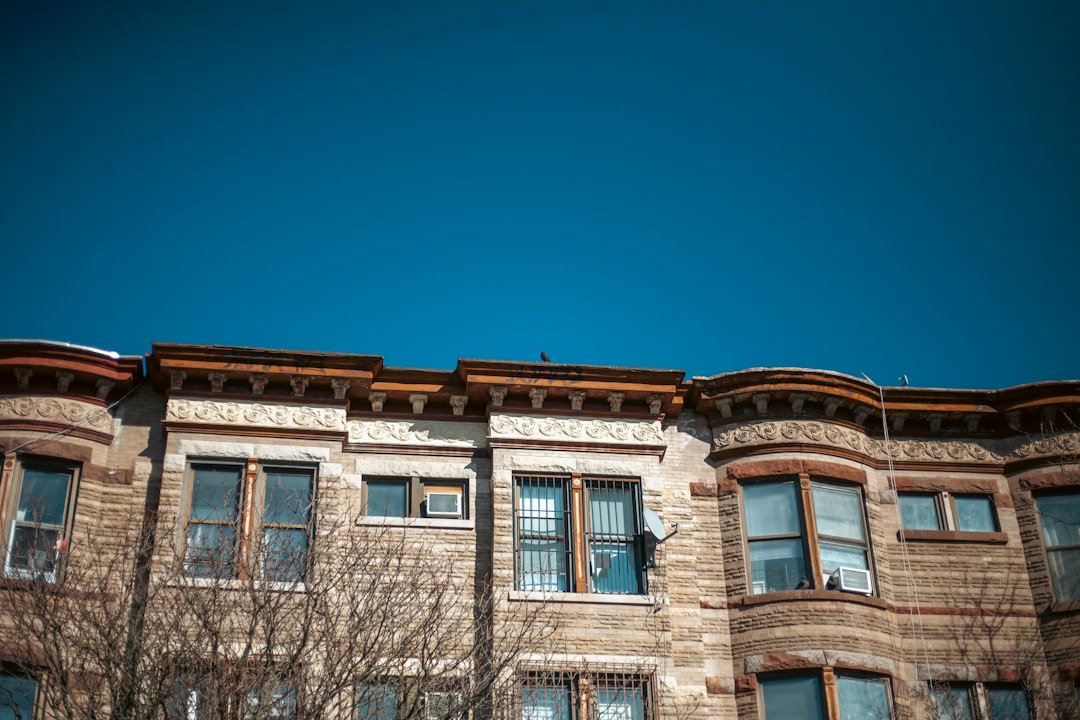 Upper stories of brick townhouses beneath a clear blue sky.