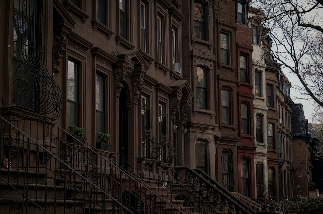 A row of brownstone townhouses with ornate iron railings and front steps.