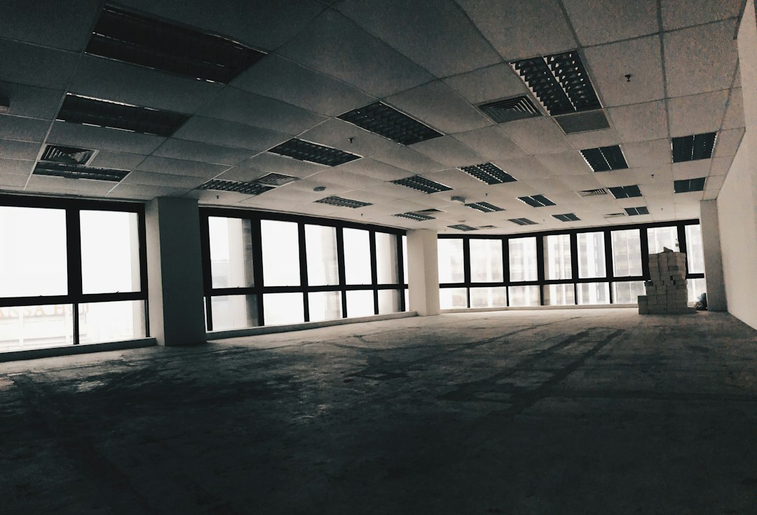 Empty commercial interior with large windows and an exposed ceiling