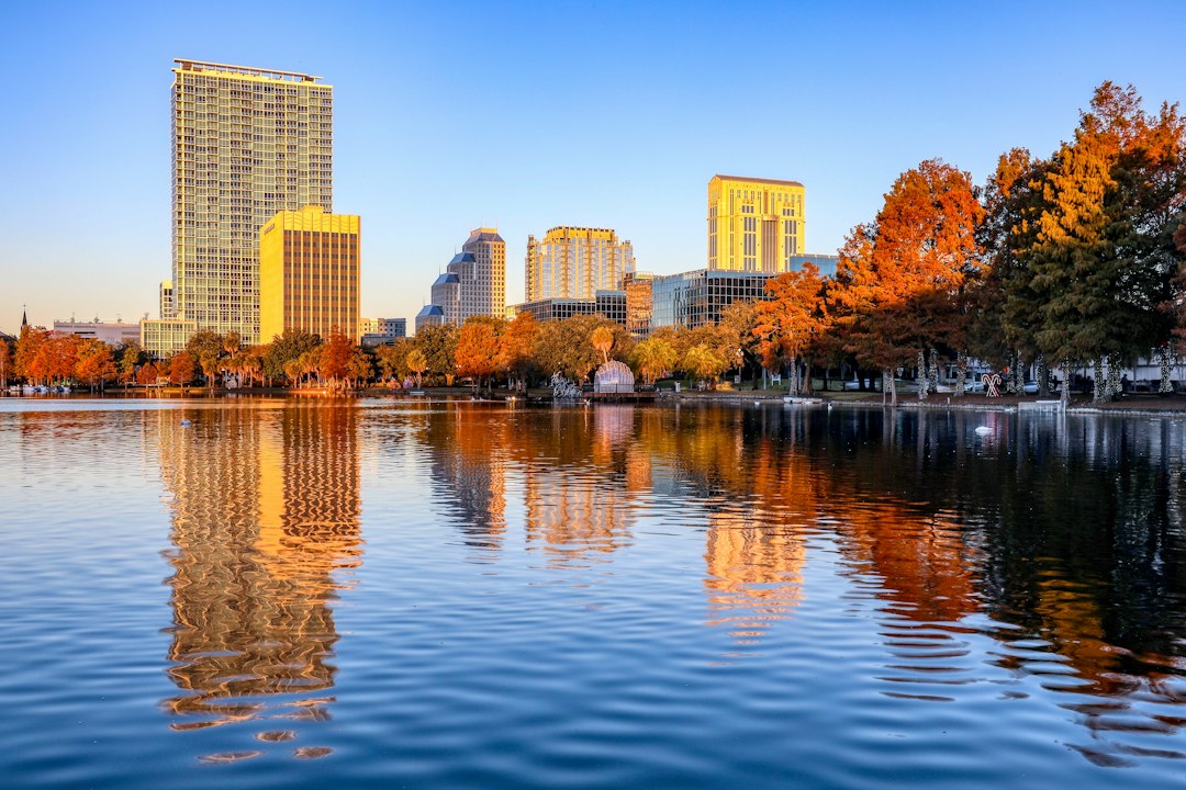 Downtown Orlando buildings and trees reflected in Lake Eola during a golden sunrise