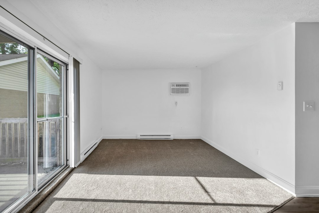 Empty carpeted room beside a sliding balcony door