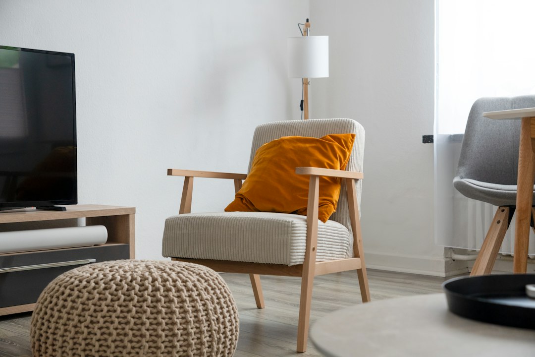 Upholstered wooden armchair with a footstool and orange cushion