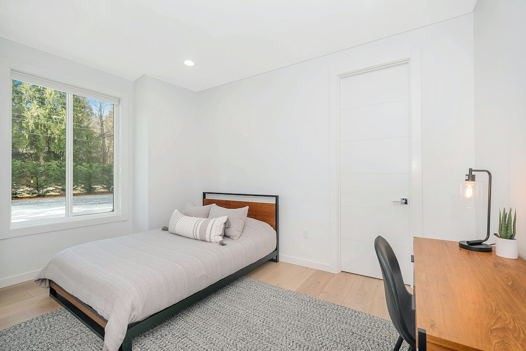 Bedroom with a low bed, desk and a large window