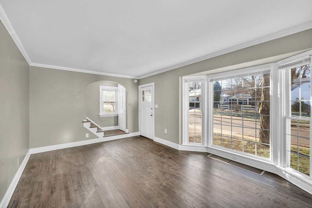 Empty living room with gray walls and a wide bay window.