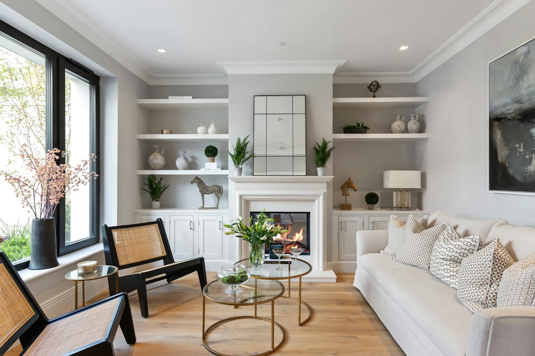 Living room with white built-in shelves, a fireplace, wood flooring, and a cream sofa