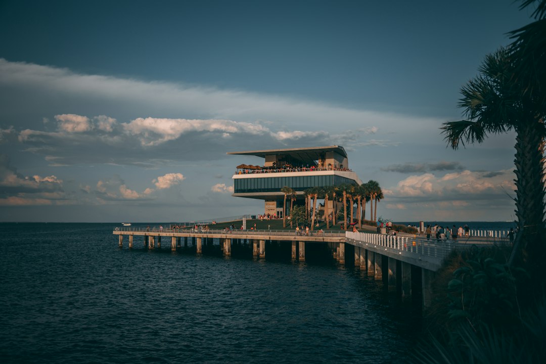 Waterfront pier and pavilion over calm water beneath dramatic clouds