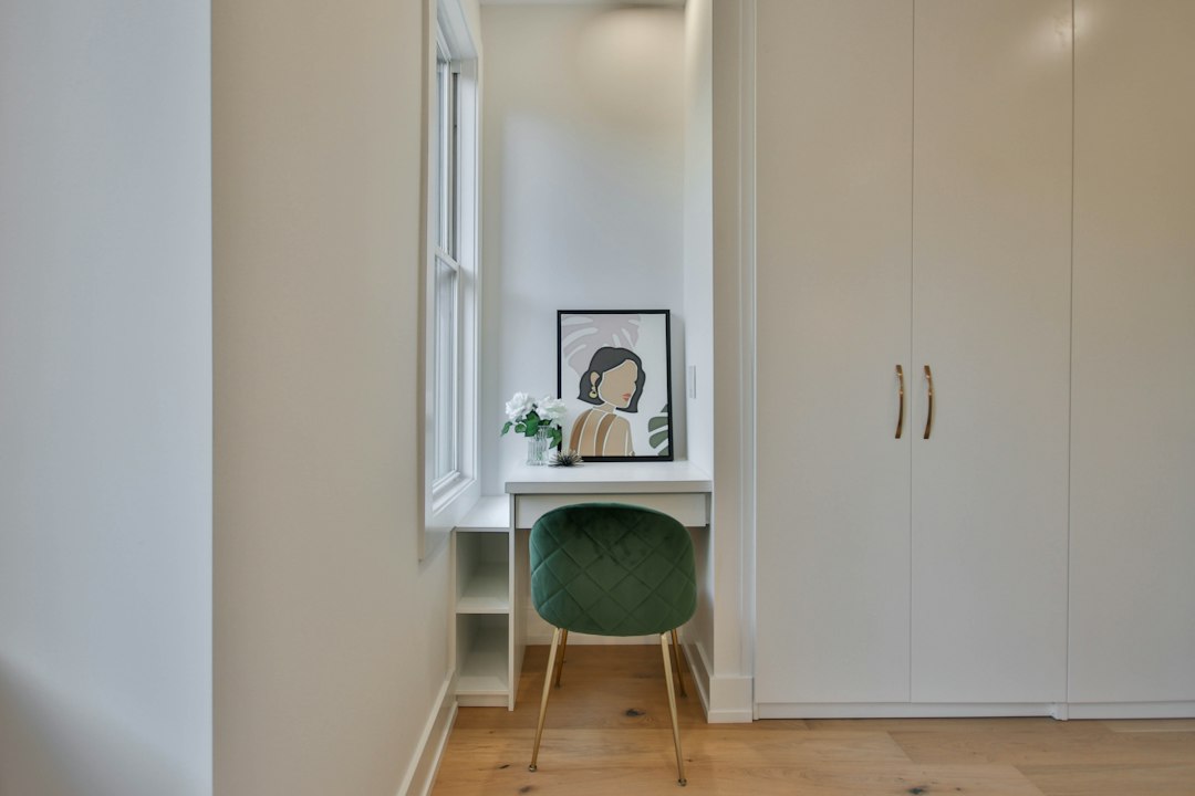 Small desk and green chair in an alcove beside a wardrobe