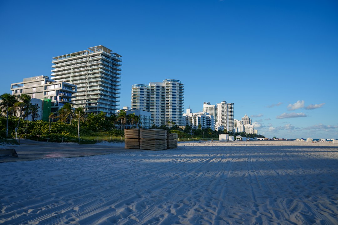 Wide sandy beach with coastal apartment buildings beneath a clear blue sky.