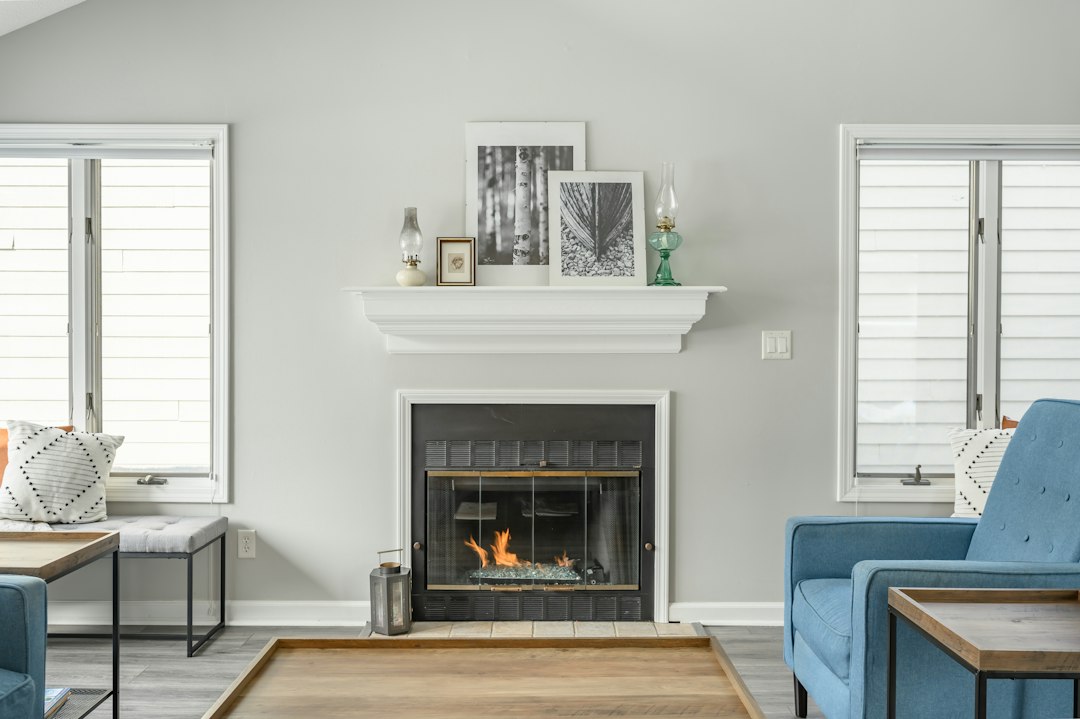 White living room with a fireplace, pale blue chairs, and striped window blinds