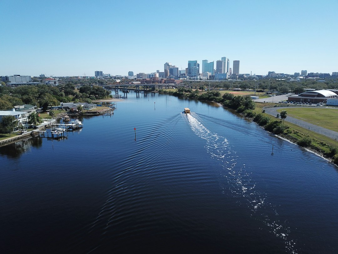 Aerial view along the Hillsborough River toward downtown Tampa, with waterfront homes and a boat wake